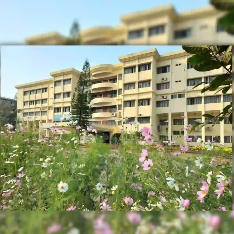 An apartment building with balconies behind a colorful garden of flowers.