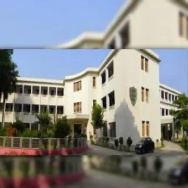 White multi-story building with trees and clear sky, slightly blurred.