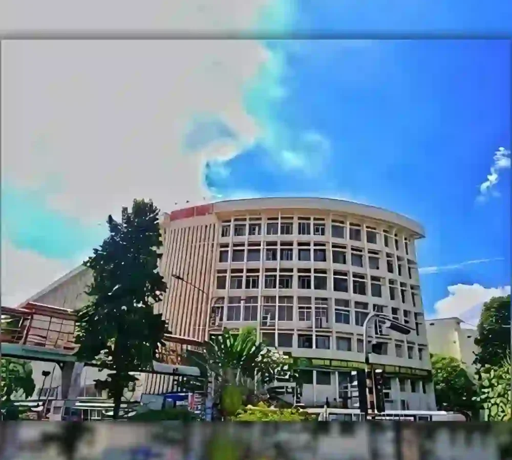 Modern multi-story building with curved facade under blue sky with clouds.