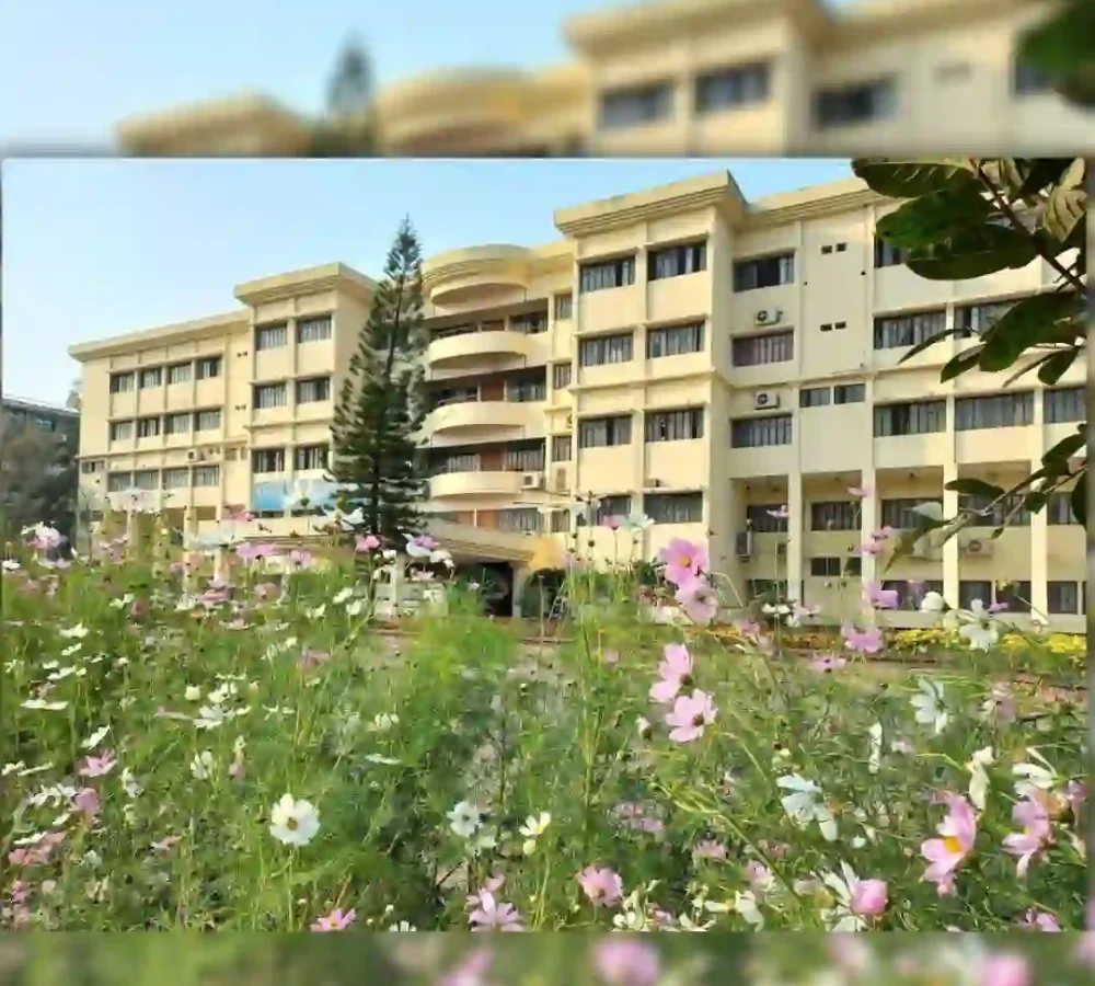 An apartment building with balconies behind a colorful garden of flowers.