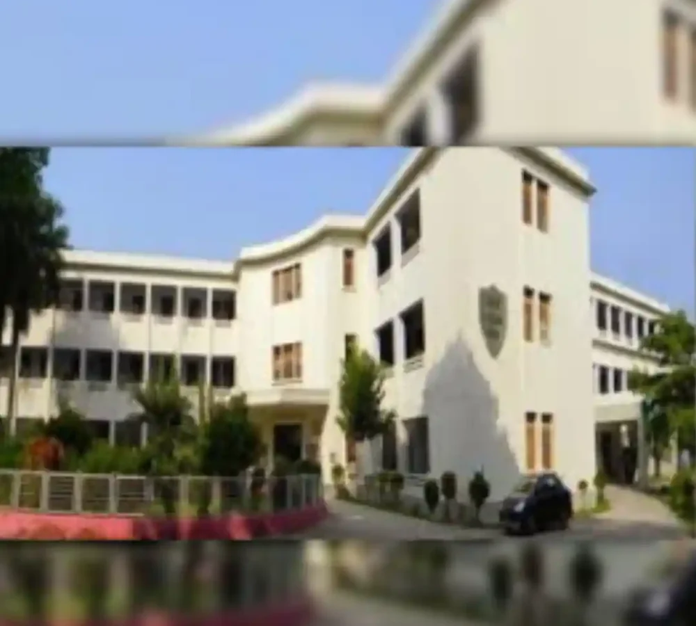 White multi-story building with trees and clear sky, slightly blurred.